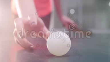年轻女子走近一张网球桌，拿起球，开始玩